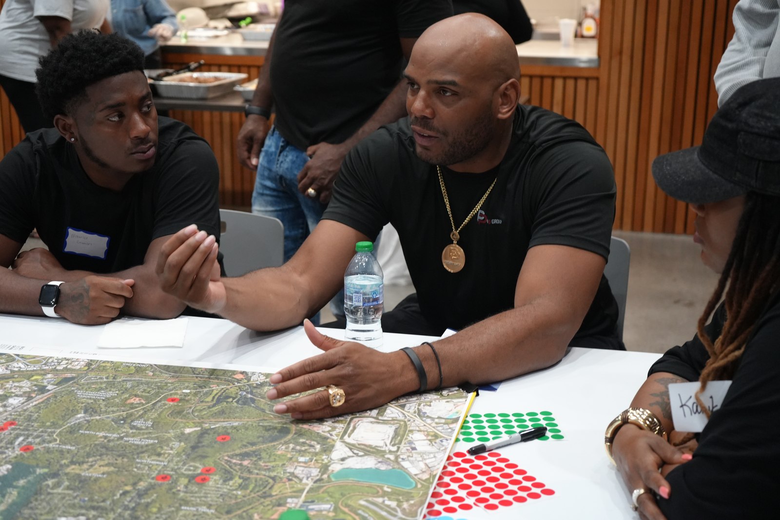 Rashad talking with neighbors at a community planning meeting, site map on the table