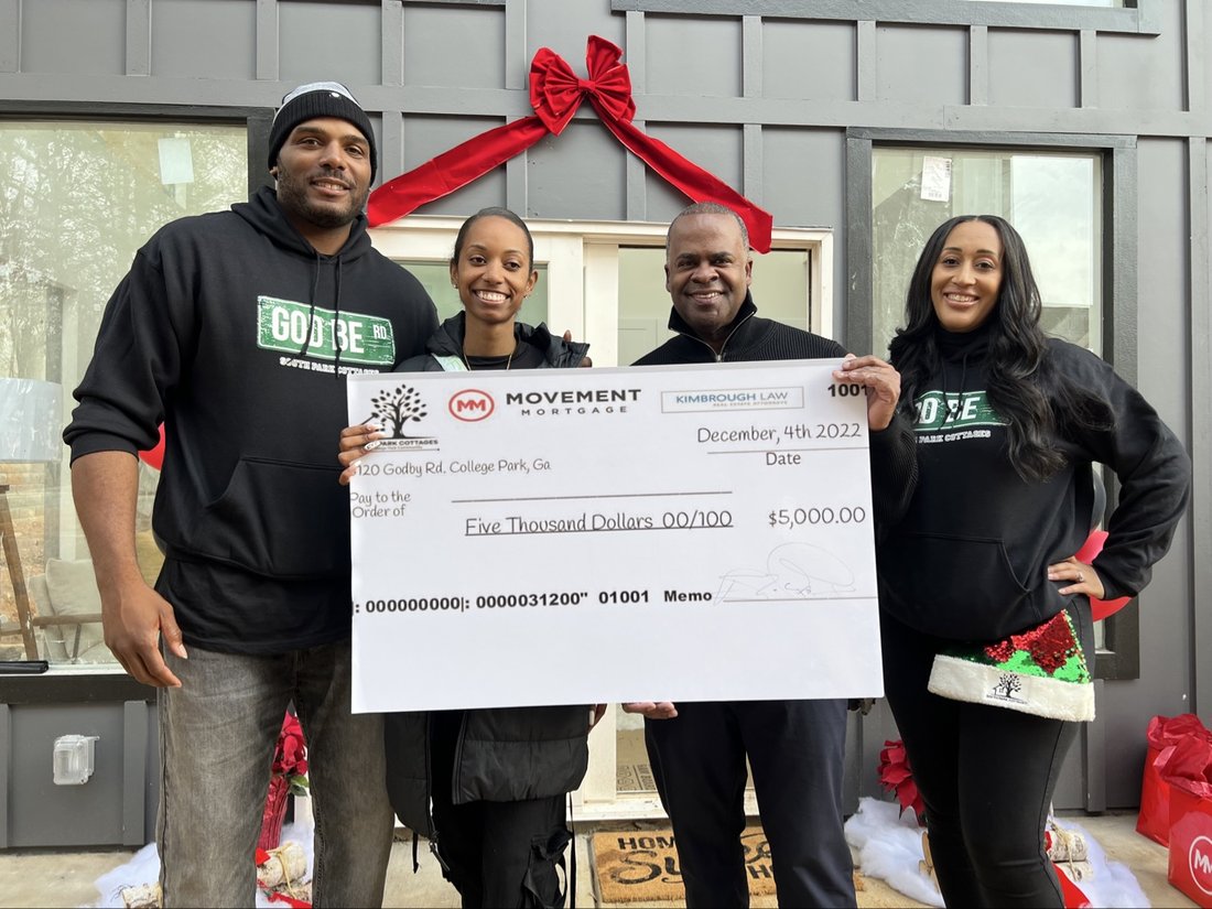 Rashad with three partners holding a $5,000 Movement Mortgage check at South Park Cottages